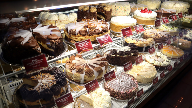 Rows of whole cheesecake varieties in a case at a Cheesecake Factory location