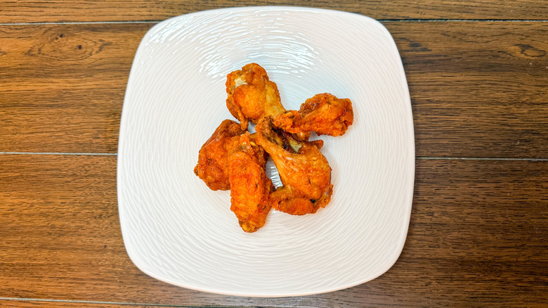 Five chicken wings stacked on white plate