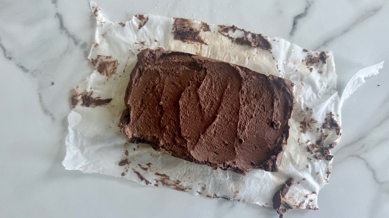 A block of uncut cauliflower fudge on baking paper on a marble counter top