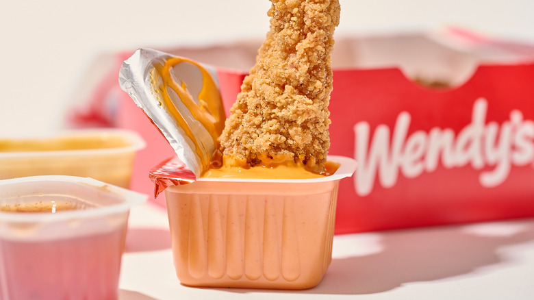 Dunking a chicken tender into hot sauce