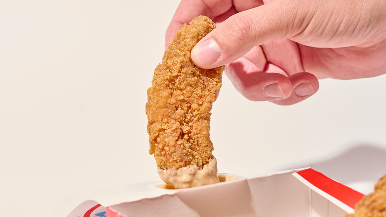Dipping chicken tender into signature sauce