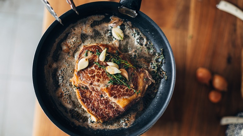 Skillet with steak, garlic, and herbs