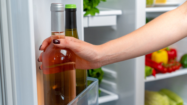 Arm grabbing a wine bottle out of the fridge