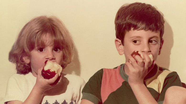 Two kids eating apples