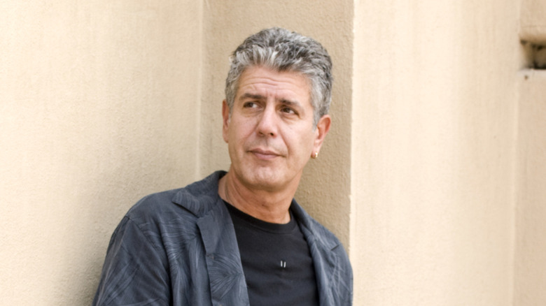 Anthony Bourdain leaning against a wall and looking off into the distance