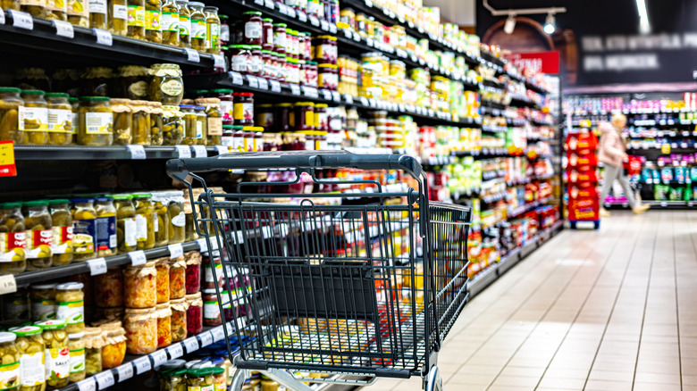A shopping cart sitting by itself in the aisle of a supermarket.