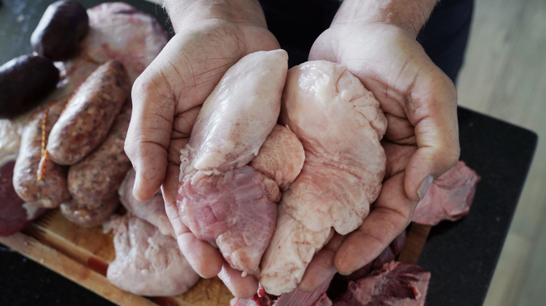 Hands holding raw sweetbreads
