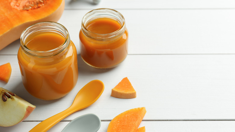 Glass jars with orange squash baby food.