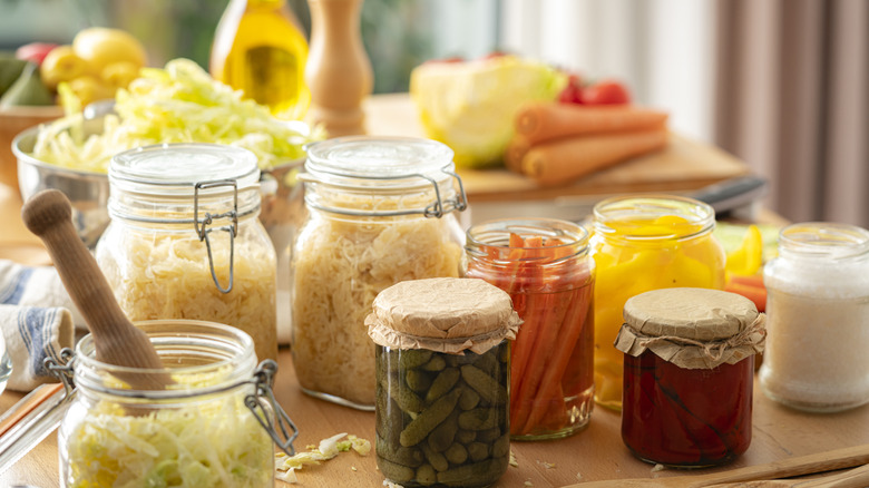 Varying glass jars set on a table, each filled with different ingredients ready for fermenting