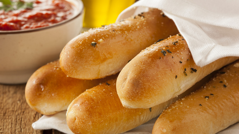 Breadsticks sit in a pile under a napkin