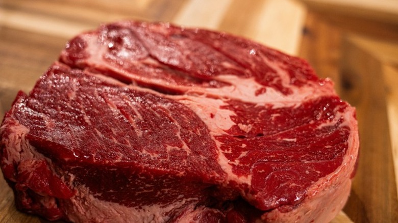 A cut of high quality USDA Prime beef with noticeable marbling sitting on a cutting board.