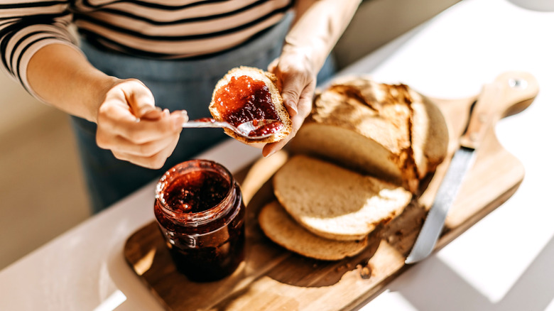 Spooning raspberry jam onto fresh bread