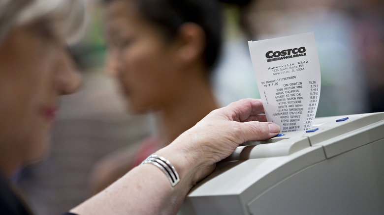 Costco cashier holding receipt as it prints out.