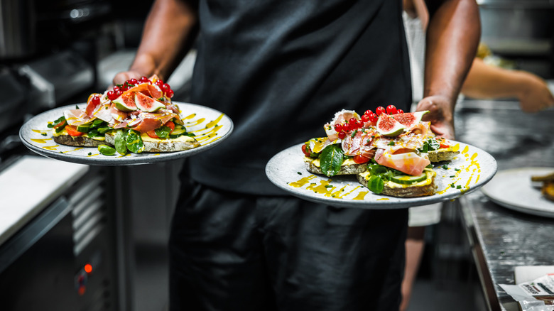A person holding two plates of the same dish
