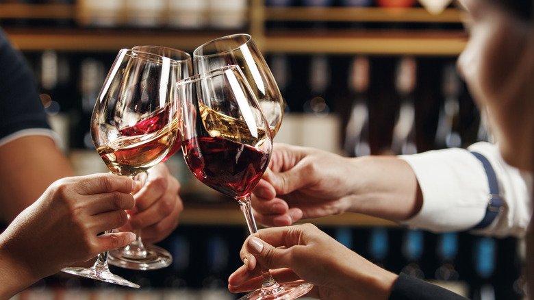 people toasting red wine glasses