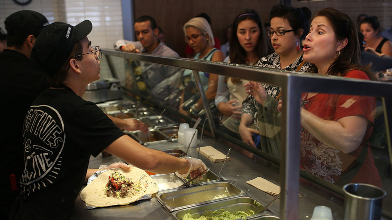 Customers ordering food at a busy Chipotle restaurant