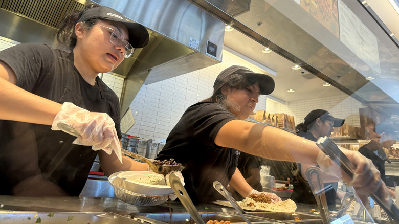Employees making food behind the counter at Chipotle