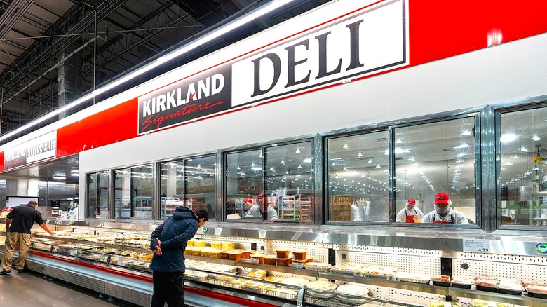 Man in a hooded jacket perusing the deli counter at Costco