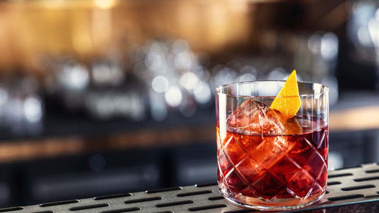 Negroni on a bar with alcohol bottles blurred in the background