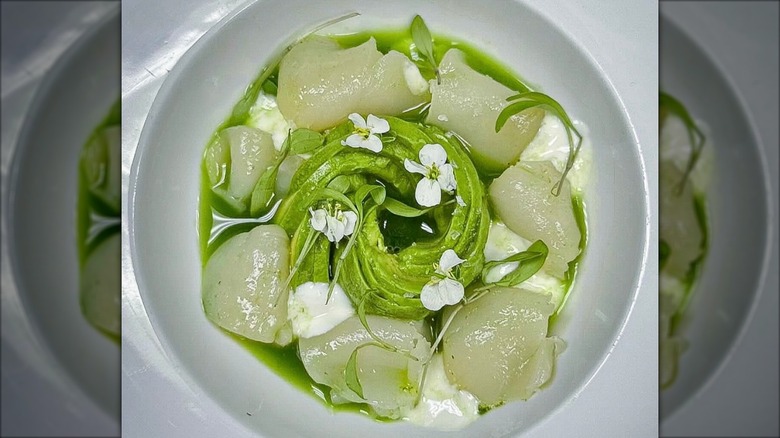 Fresh Hokkaido Scallops over avocado Gazpacho, with horseradish yogurt in a white bowl