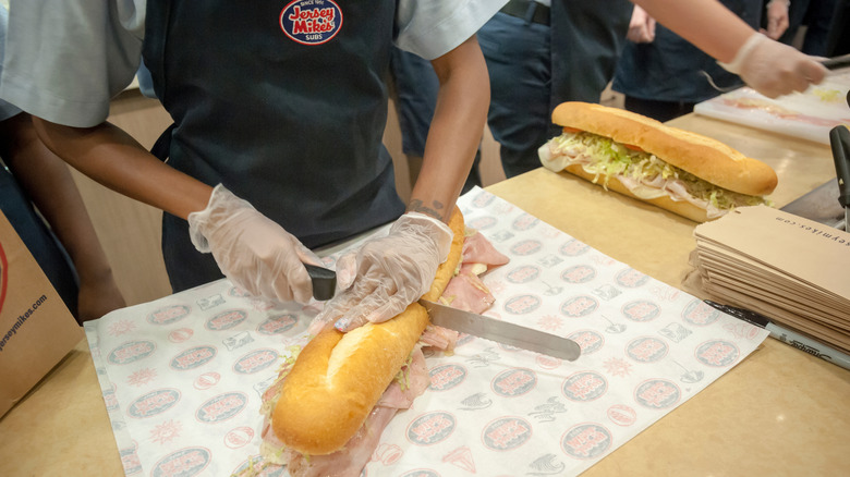Worker slicing a sub in half at a Jersey Mike's