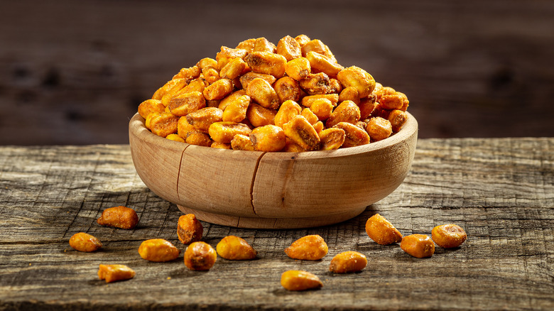 A bowl of corn nuts on a wooden table