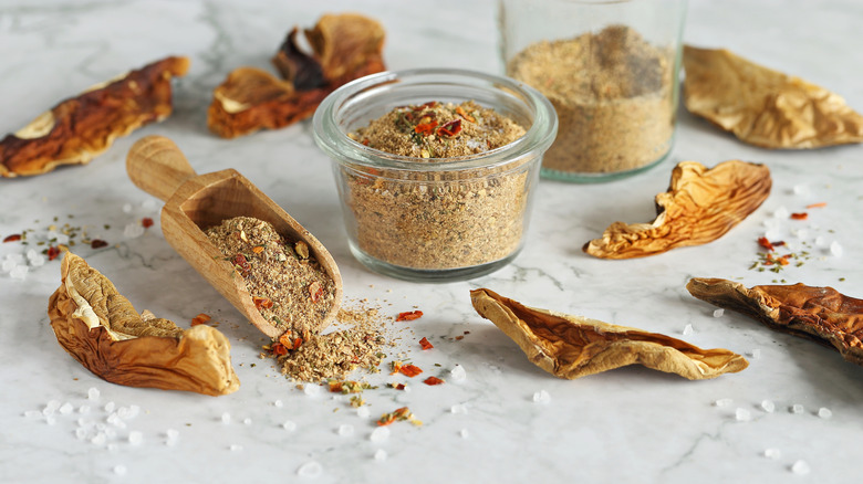 Assorted dried mushrooms and mushroom powder in small glass jar