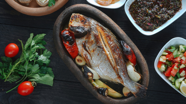 Grilled fish and veggies typical of the Mediterranean diet are photographed from above.