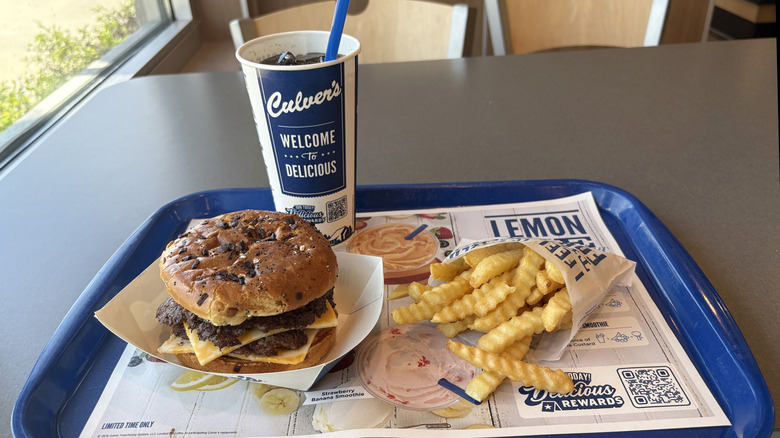 Culver's burger, fries, and a soft drink at a table