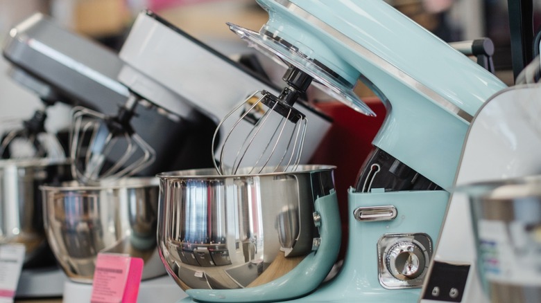 A row of KitchenAid mixers from various years and in different colors on display.