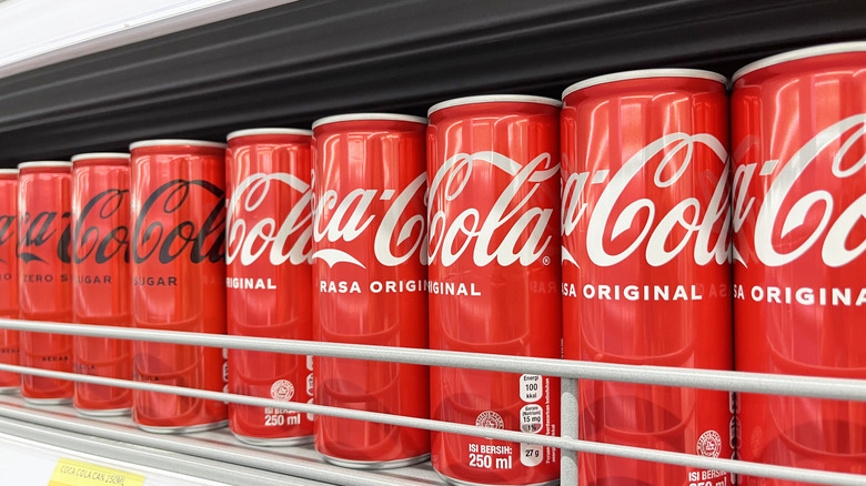Cans of Coke on the grocery store shelf
