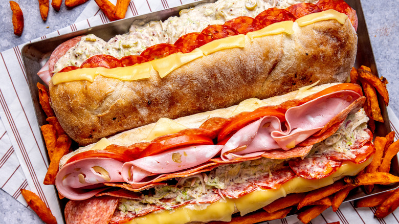 A grinder sandwich filled with meats and cheeses is photographed from above.