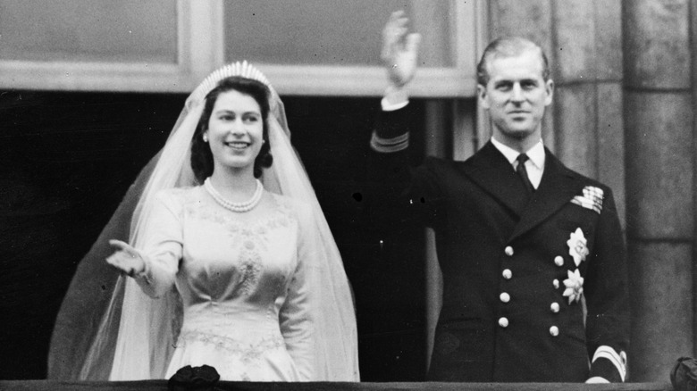 A black and white photo of Queen Elizabeth II and Philip waving to crowds on their wedding day.