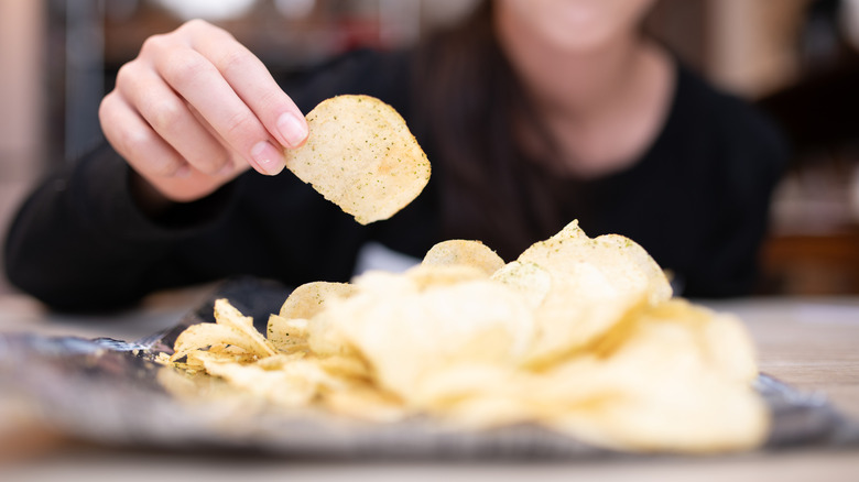 A hand holds a potato chip