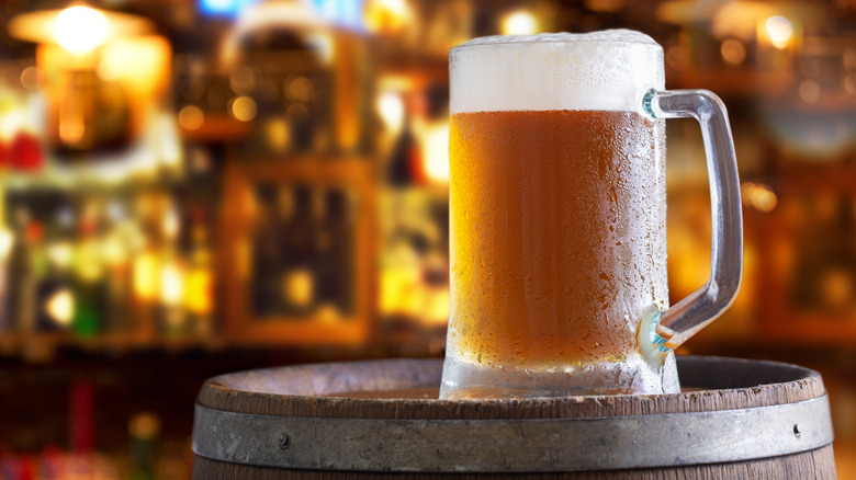 Cold mug of beer on a wooden barrel