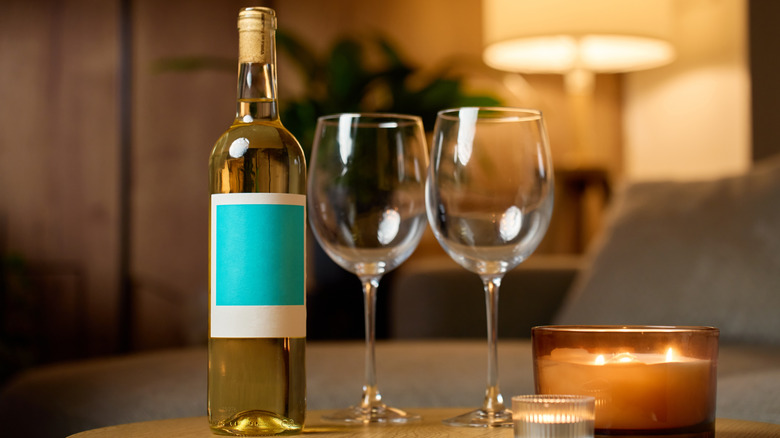white wine bottle next to two empty glasses