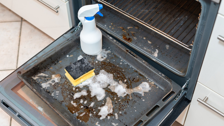 A dirty oven tray with foam cleaner.