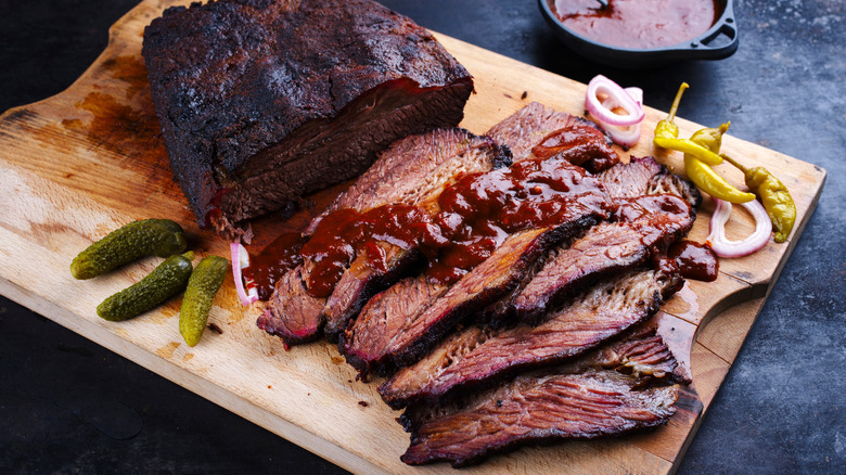 Sliced brisket with barbecue sauce on a wooden cutting board