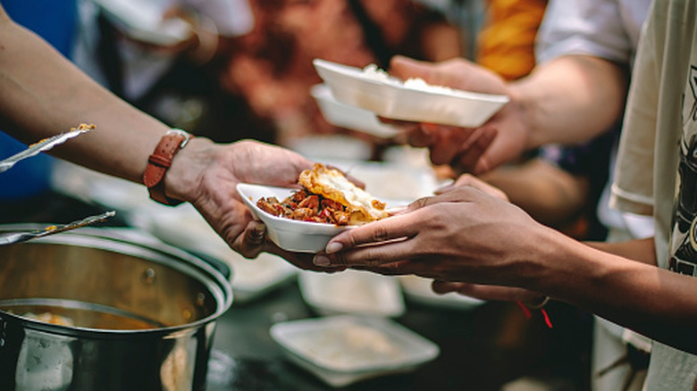 Hands of volunteers passing out food at a food bank.