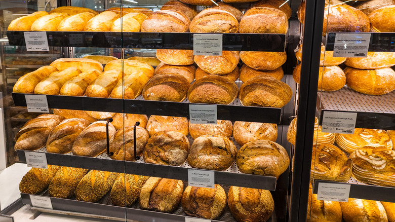 Assorted breads on display in a glass case at Whole Foods