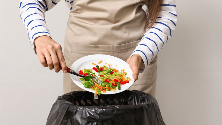 Person scraping food into a bin
