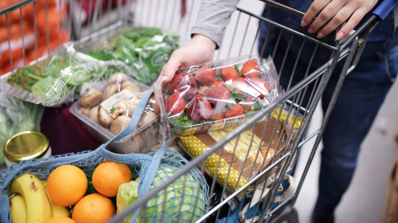 A cart full of produce with a person shopping at Whole Foods.