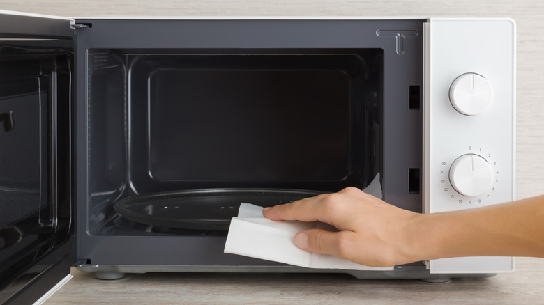 Hand wiping the interior of a microwave with a cloth