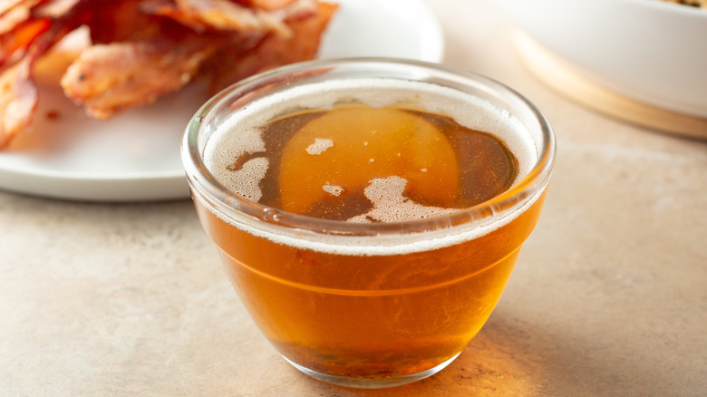 A small cup of bacon grease, with a bit of foam on top