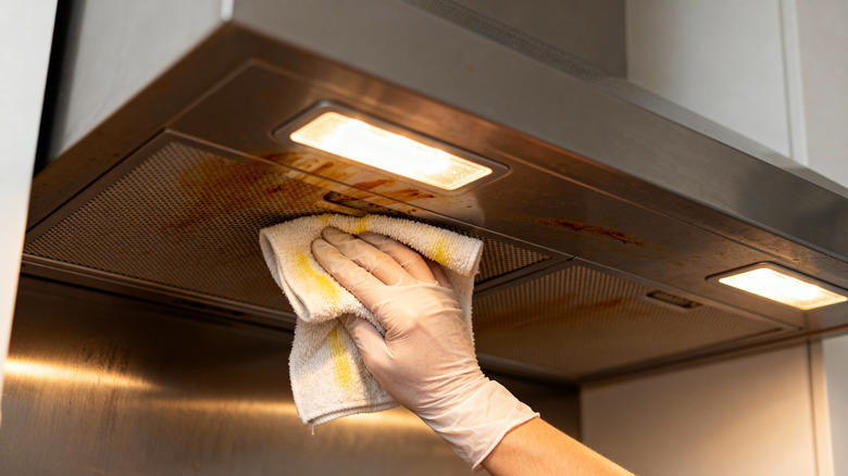 person cleaning grease from a range hood