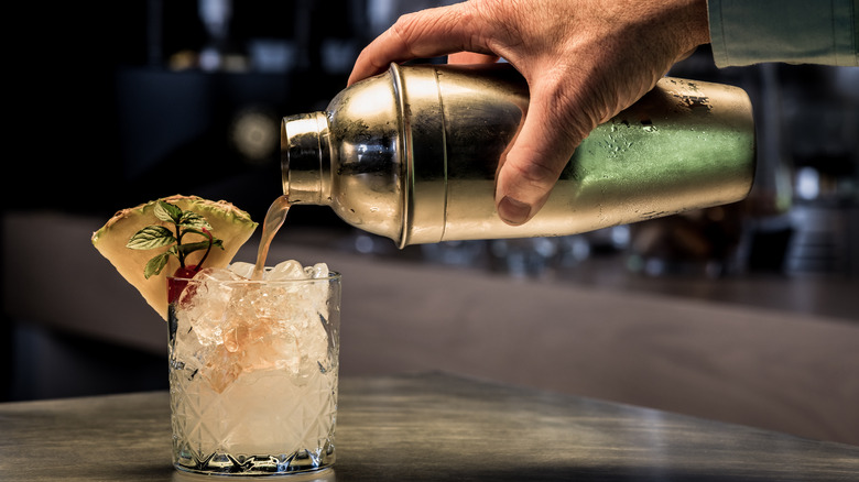 Hand pouring cocktail from shaker 