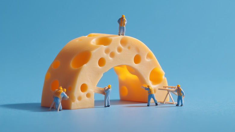 Toy people dressed as construction workers placed around plastic cheese