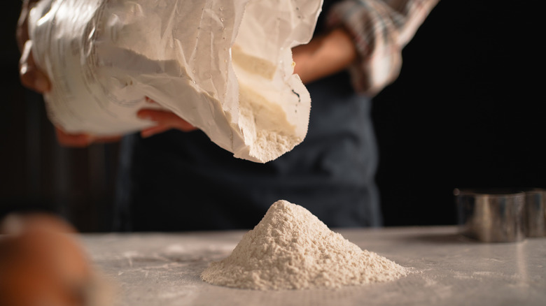 Flour being poured onto a kitchen counter from a bag.