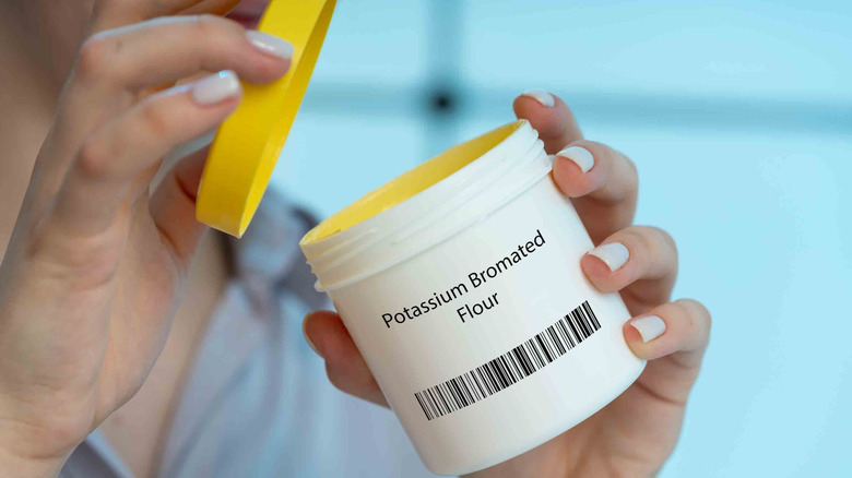 A hand opening a jar marked with "potassium bromated flour".