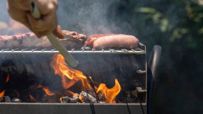Person grilling meat over a charcoal grill